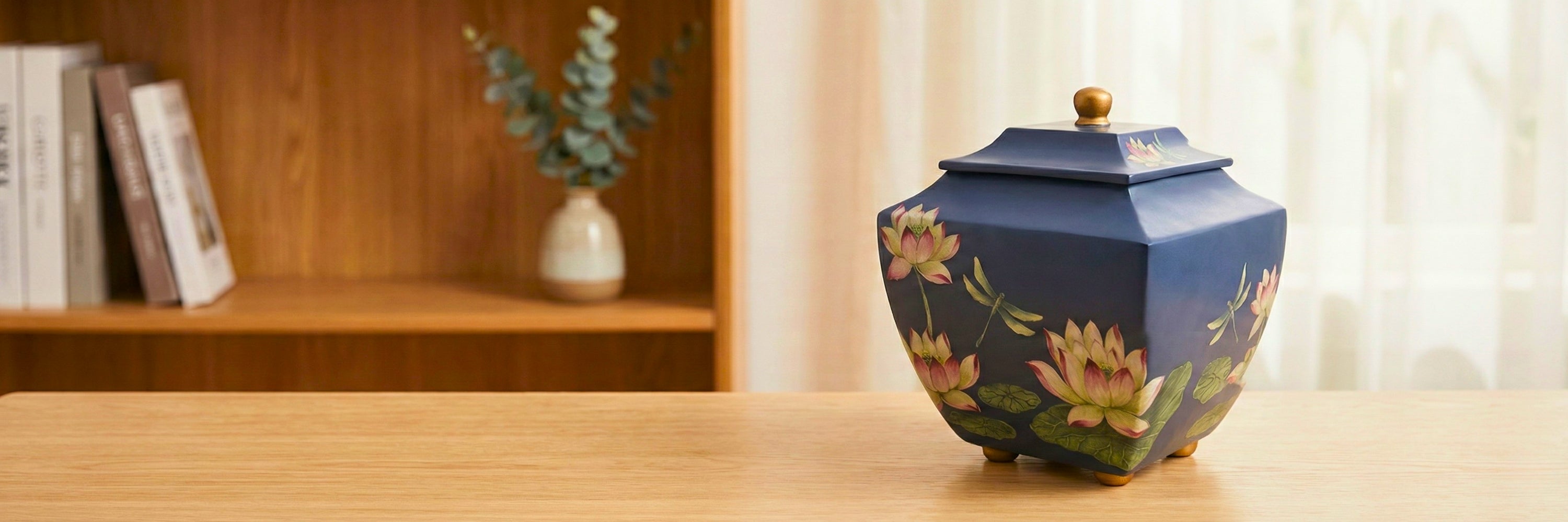 Navy blue cremation urn with hand-painted lotus flowers and dragonflies on wooden surface — Magnolia Memorial Marketplace